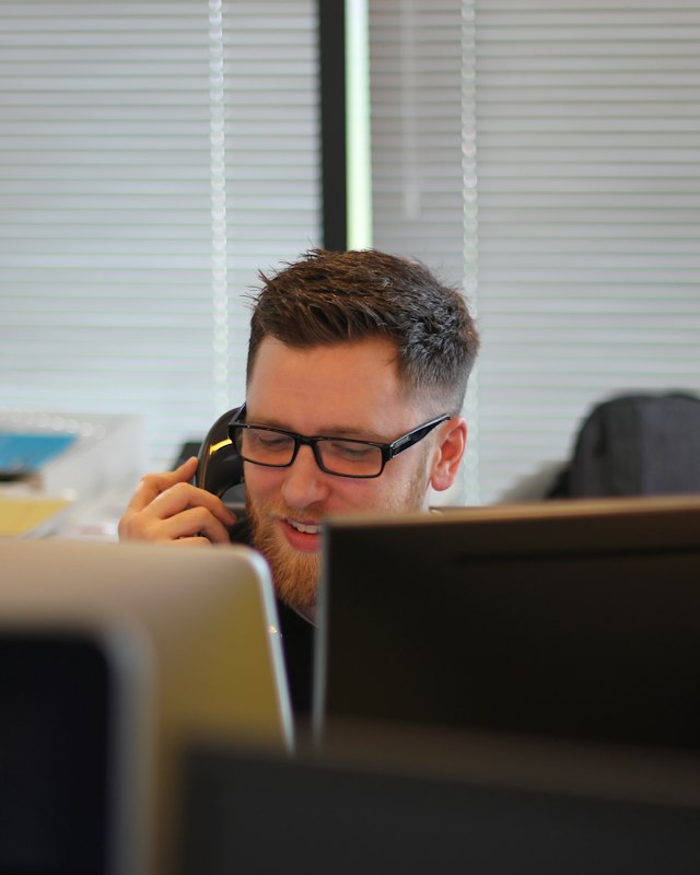 Man in glasses on a phone call at an office desk